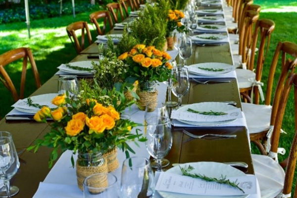 outdoor table decorated with plates, wine glasses, menus, and flowers