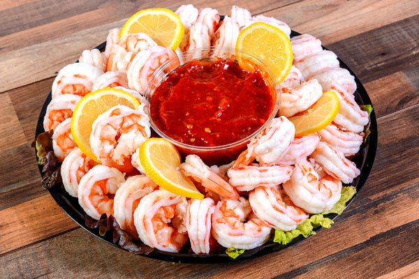 shrimp cocktail, cocktail sauce, and sliced lemons arranged on a platter